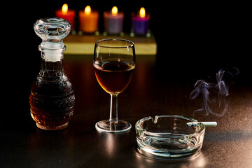 glass of alcohol and bottle with cigarette isolate on black 
