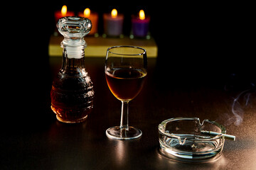 glass of alcohol and bottle with cigarette isolate on black 