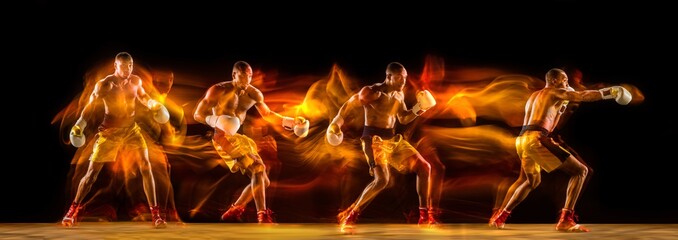 Professional african-american boxer training on black studio background in mixed light. with...