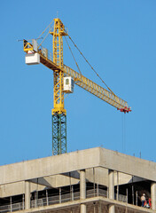 Building under construction with a crane and worker