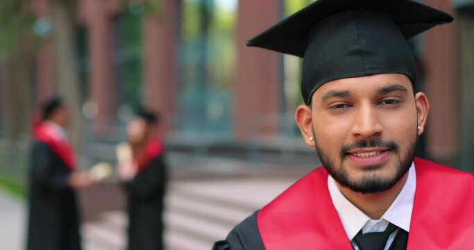 Young graduated boy holding his graduation degree convocation ceremony. Attractive multiracial student graduate posing towards the camera during the ceremony