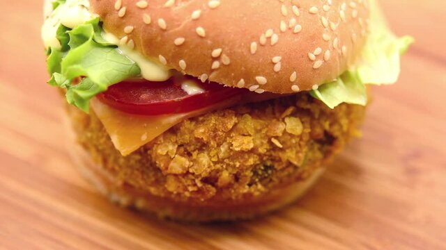 Crispy chicken burger footage rotating on wooden table