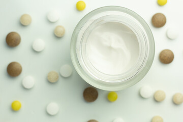 Top down view of supplements for clear skin (vitamin C, zinc, ashwagandha, vitamin B) and a jar of moisturising cream.