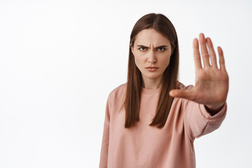 Stop it. Serious and determined woman extend palm and say no, forbid and disagree, condemn smth...