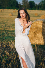 Naklejka na ściany i meble beautiful woman in a white dress walks across the field.