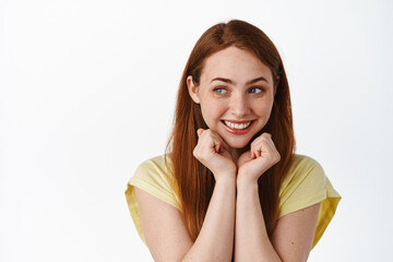 Cute and silly ginger girl, smiling and looking romantic aside at logo, lean on hands and daydreaming, thinking of something nostalgic, white background