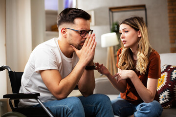 Young sad man in a wheelchair. Girlfriend comforting her sad boyfriend.