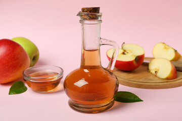 Homemade apple vinegar and ingredients on pink background