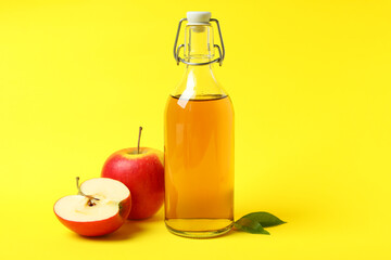 Homemade apple vinegar and ingredients on yellow background