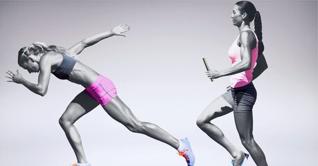 Two diverse female athletes holding baton running against grey background