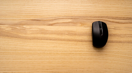 Black wireless mouse on wooden table with copyspace