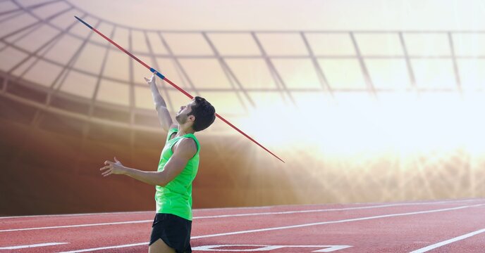 Caucasian male athlete throwing a javelin against sports field in background