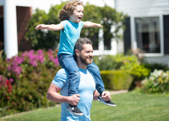 Happy man carry son kid sitting on fathers shoulders summer outdoors, piggy-back