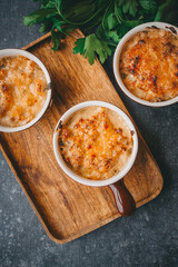 Julienne in portions, Mushrooms with cream and cheese casserole, Restaurant food on a dark background, Top view