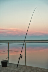 The bottom fishing rod stands with a stretched line against the background of the evening sky.