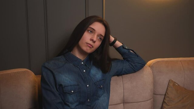  Portrait of upset tired woman sitting on couch at home. Stressed woman feeling tired.