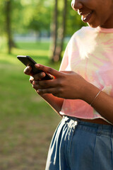 Close-up of African young woman typing a message on mobile phone while standing outdoors