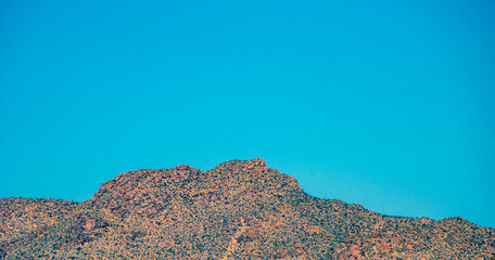 Barren red rocky mountain peak under a blue sky