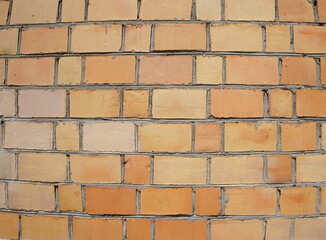 Background with a orange  brick wall, close up. Old brick wall with holes, cracks.  Texture large brick.