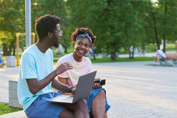 African young couple working on laptop together during their meeting in the park