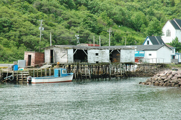 Weathered fishing shack with storage containers and a docked fishing boat