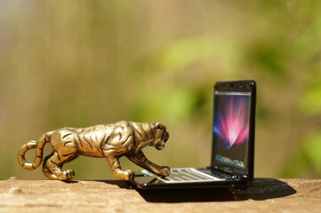 Metal tiger figurine with a laptop close-up. Business concept.