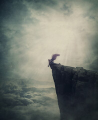 Surreal scene with an angel fallen in limbo, sitting alone on the edge of a cliff between the skies. Magical winged creature expelled from paradise. Metaphorical and conceptual imaginary world view - obrazy, fototapety, plakaty