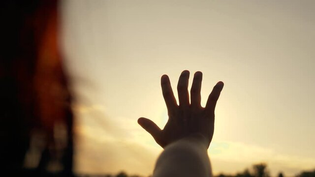 Close-up of a man girl hand at sunrise. hand reaches for the sun against the background of the sky. Sunrise hand silhouette reaching dream. hand girl of a man in the sunbeams of the sky.