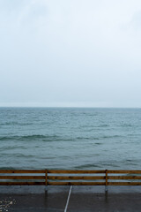 Wet wood railing in front of the sea on a cloudy windy day