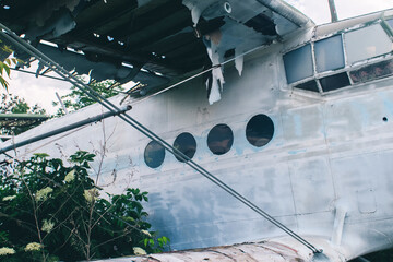 A close-up of an old wrecked passenger plane that has been decommissioned and stands for tourists. The fuselage shows traces of rust and chips. Parts of the metal structure are visible on the wings