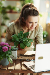 florist in rubber gloves in sunny day using laptop