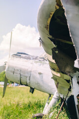 A close-up of an old wrecked passenger plane that has been decommissioned and stands for tourists. The fuselage shows traces of rust and chips. Parts of the metal structure are visible on the wings