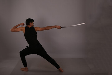Fototapeta na wymiar Fighter with vintage sword on gray background