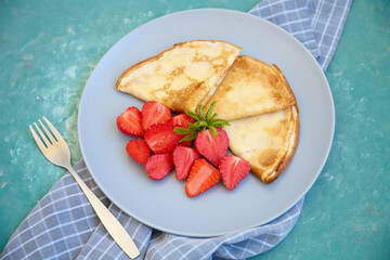 Pancakes, thin pancakes with fresh strawberries. On an empty background. Copy space.