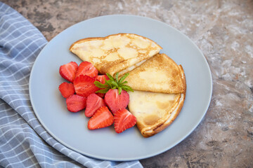 Pancakes, thin pancakes with fresh strawberries. On an empty background. Copy space.