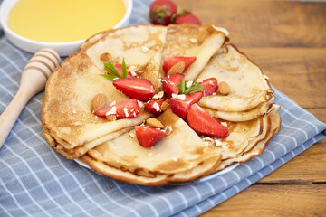 Pancakes, thin pancakes with fresh strawberries. On a wooden background. Copy space.