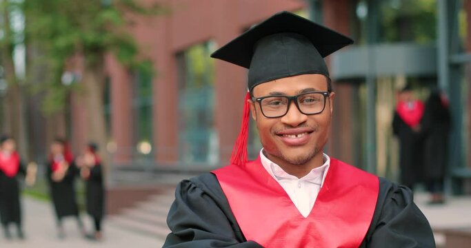 Young graduated boy holding his graduation degree convocation ceremony. Attractive multiracial student graduate posing towards the camera during the ceremony