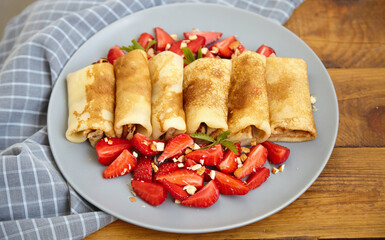 Pancakes, thin pancakes with fresh strawberries. On a wooden background. Copy space.