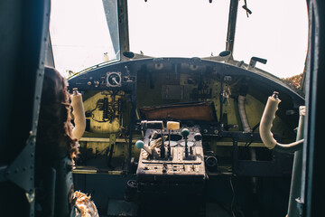 A close up of the cockpit of a vintage airplane. The steering wheel, dashboard, seat and climb...