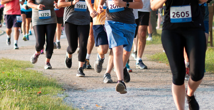 Runners in a crowded race running a 5K around a lake on a dirt trail in a park