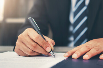 Businessman writing signing on document in office