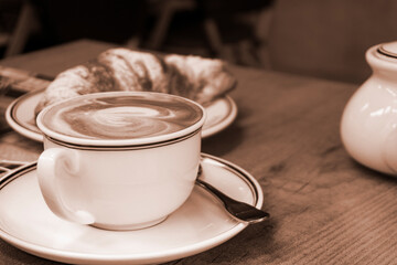 Cup of cappuccino coffee and croissant close-up top view. Appetizing delicious breakfast
