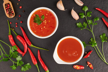 .red hot chilli sauce. tomato ketchup, chilli sauce, puree with chili pepper, Vegetables, tomatoes and garlic. on on black stone background. top view