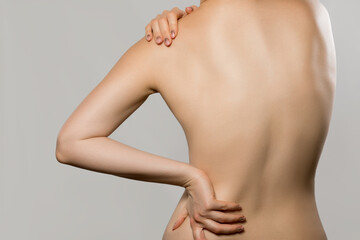Woman having backache, isolated on gray background. Scoliosis. Spinal cord problems on womans back....