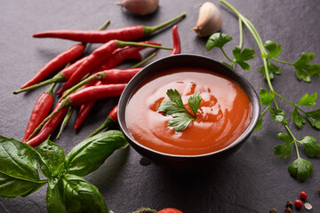 .red hot chilli sauce. tomato ketchup, chilli sauce, puree with chili pepper, Vegetables, tomatoes and garlic. on on black stone background. top view
