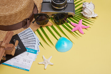 Fototapeta na wymiar Flat lay traveler accessories on yellow background with palm leaf, camera, shoe, hat, passports, money, air tickets, airplanes and sunglasses. Top view, travel or vacation concept. Summer background.