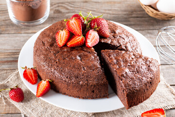Piece of delicious fresh homemade chocolate sponge cake with strawberry on table