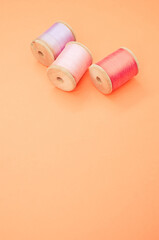 Colorful sewing threads isolated on a pastel orange background with free space for text