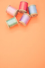 Colorful sewing threads isolated on a pastel orange background with free space for text