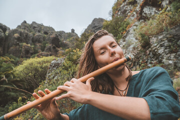 young caucasian woman playing bansuri in the mountains © remi